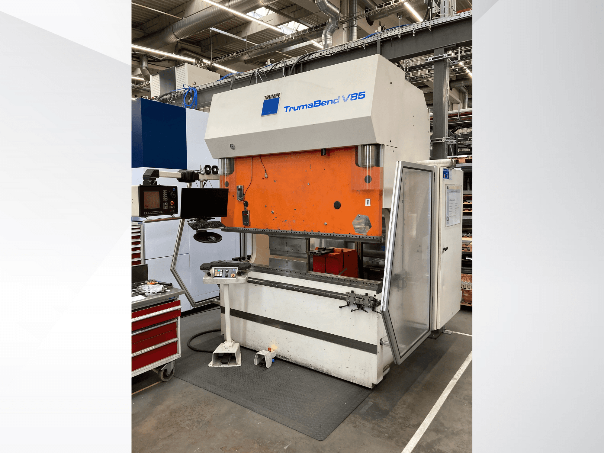 Згинальний верстат TruMatic V85 на заводі, з помаранчевою передньою панеллю, екраном керування та відкритими боковими дверима, вид збоку.