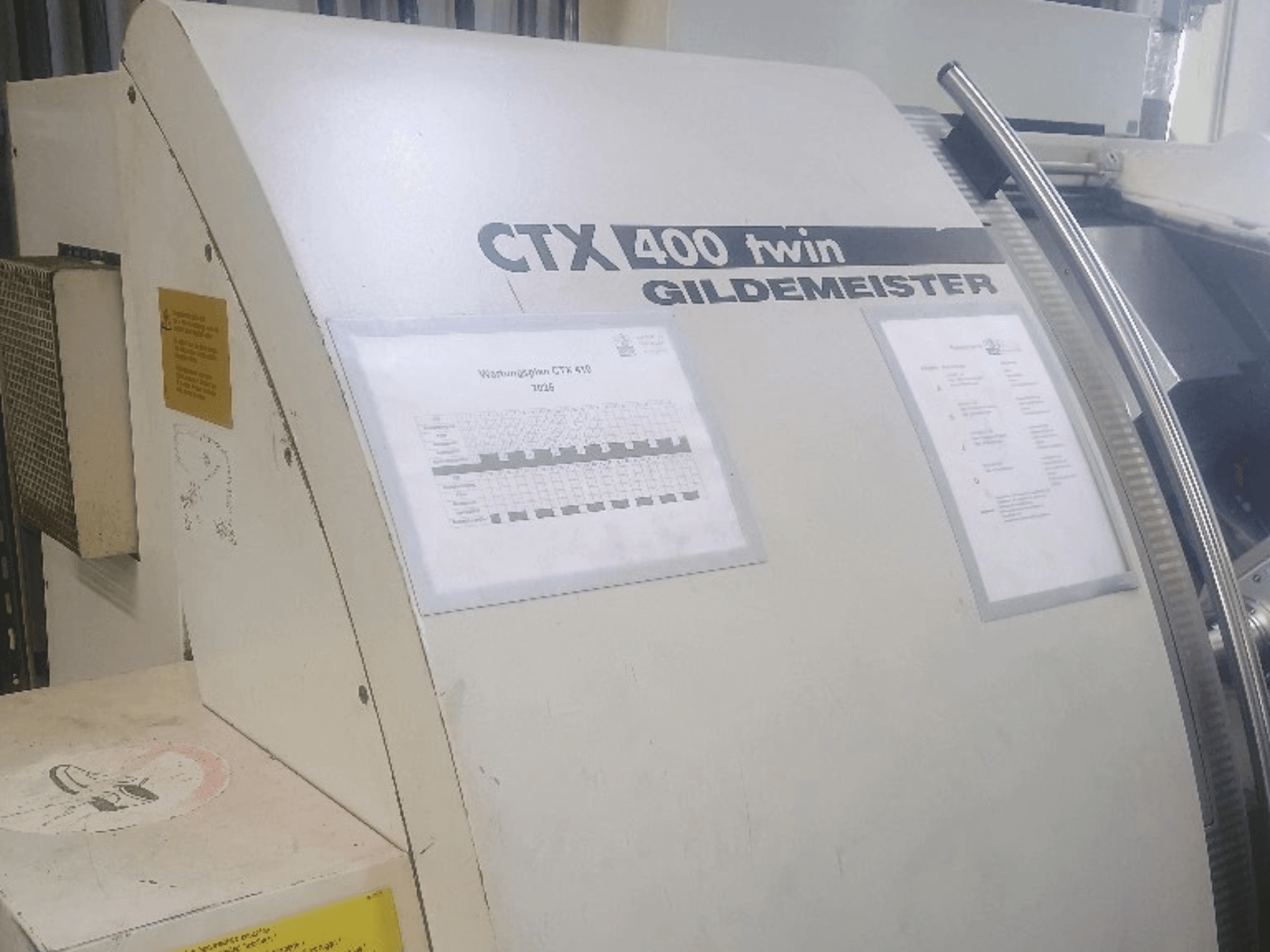 Двошпиндельний горизонтальний токарний верстат Gildemeister CTX 400, вид спереду, на якому видно панелі управління та технічну документацію.