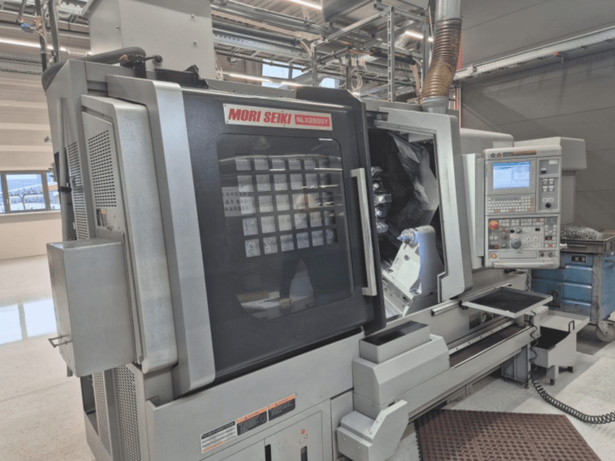 Токарний верстат з ЧПК MORI SEIKI NL2500Y у заводських умовах, вид спереду з панеллю керування та камерою для заготовки.