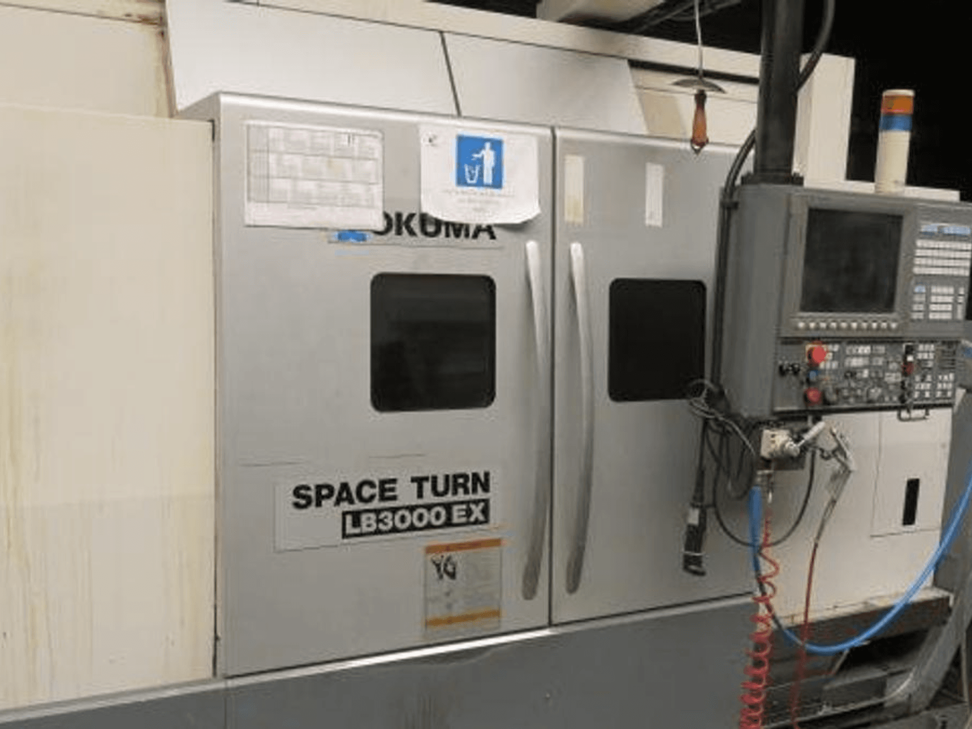 Токарний верстат з ЧПК Okuma Space Turn LB3000 EX, вид збоку, з панеллю керування, двома дверцятами та видимою електропроводкою.