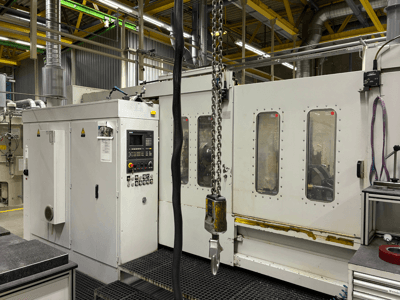 Промисловий верстат з ЧПУ з панеллю керування, вид збоку; має вікна, ланцюги та металеві компоненти в заводському виконанні.