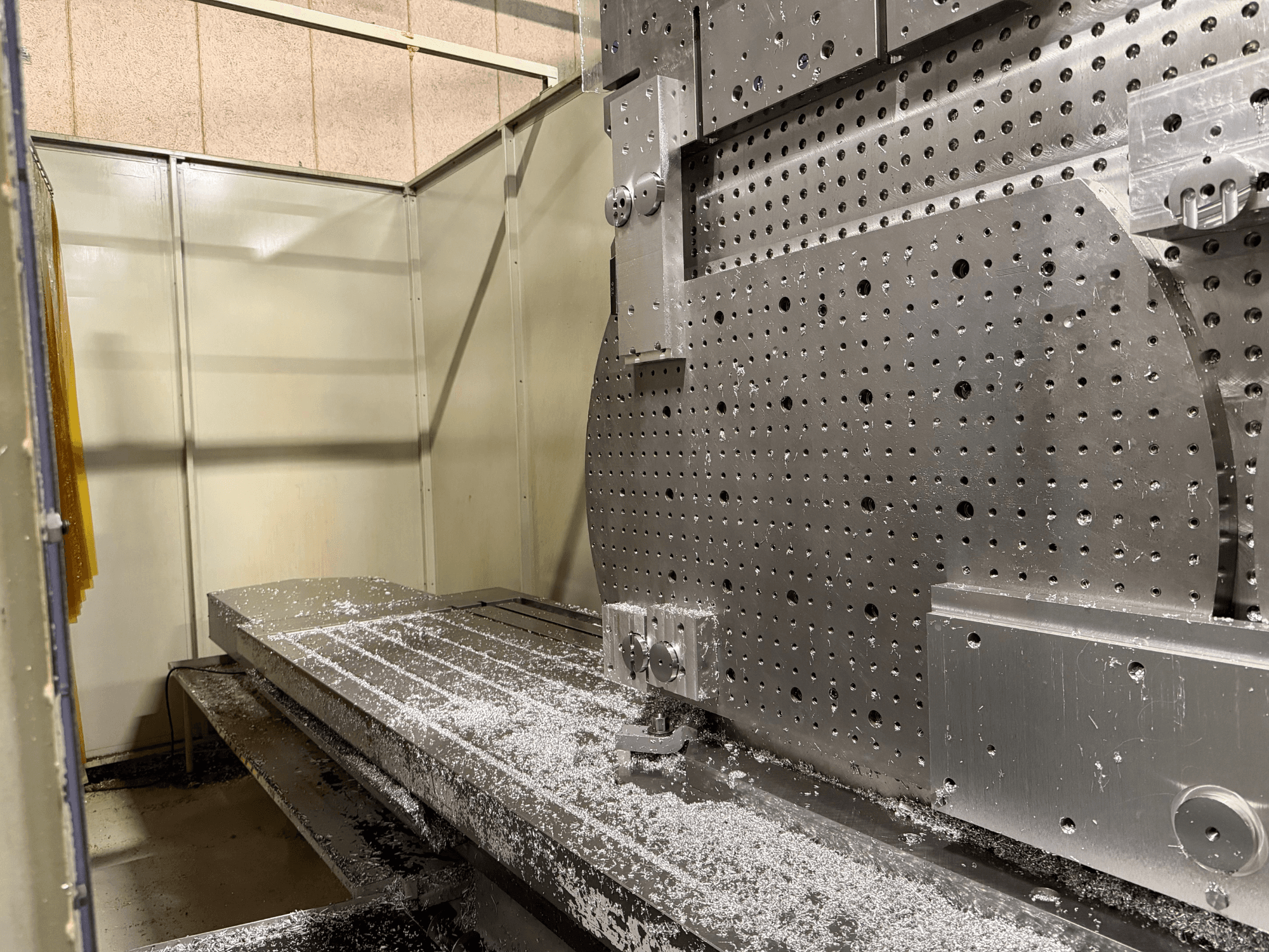 Універсальний обробний центр KIHEUNG KNC-U1000 спереду крупним планом, на якому показано металевий робочий стіл з алюмінієвою стружкою.